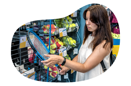 A customer examines a tennis racket at a sporting goods store. A customer examines a tennis racket at a sporting goods store.