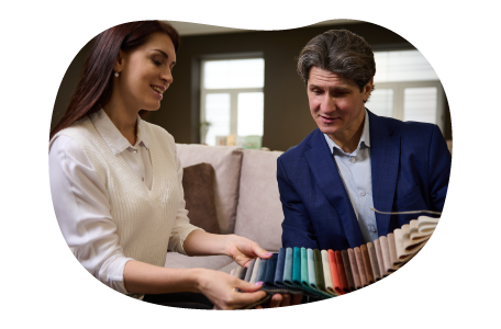 An employee at an upholstery shop shows a swatch of color samples to a customer. An employee at an upholstery shop shows a swatch of color samples to a customer.