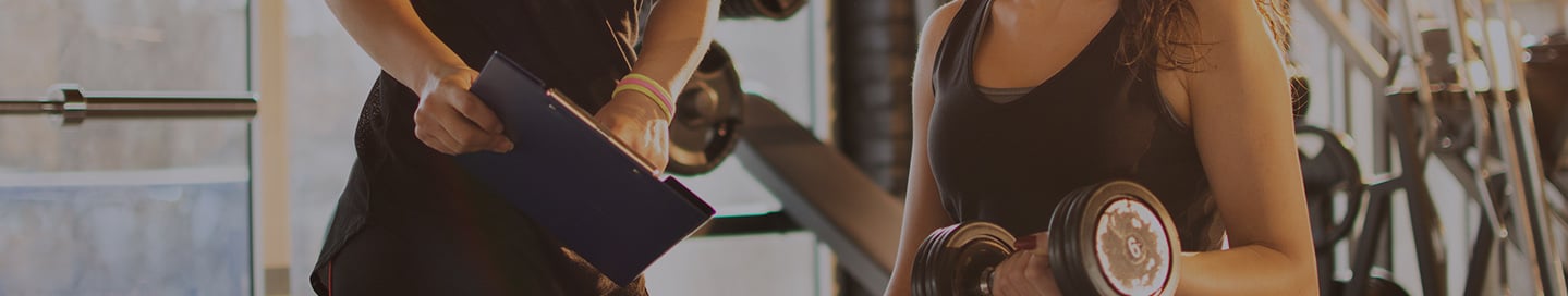 An athletic trainer explains fitness goals to a client An athletic trainer explains fitness goals to a client