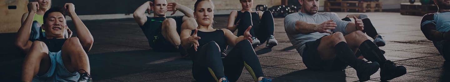 Several people doing sit-ups in an exercise class. Several people doing sit-ups in an exercise class.