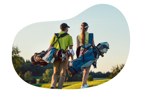 Two golfers carry their gear across a golf course. Two golfers carry their gear across a golf course.