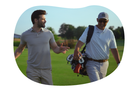 A golf instructor and their student walk across a golf course.