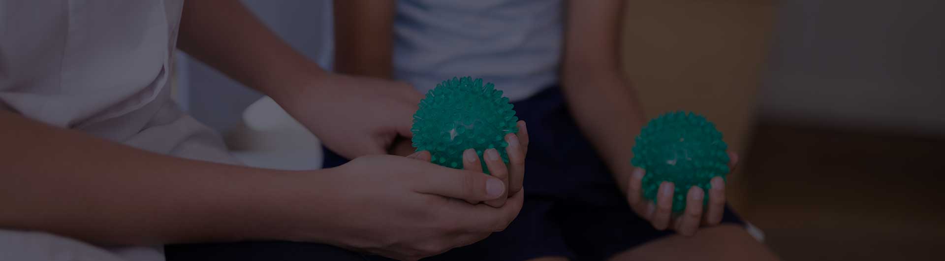 Female therapist and boy holding stress balls.