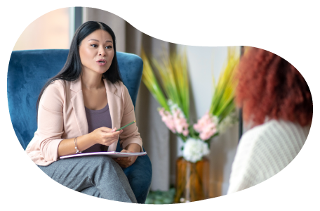 Psychologist sitting in a chair speaking with a patient in an office. Psychologist sitting in a chair speaking with a patient in an office.