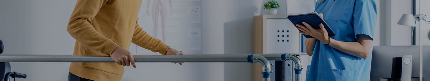 A rehabilitation counselor assists a patient with walking. A rehabilitation counselor assists a patient with walking.
