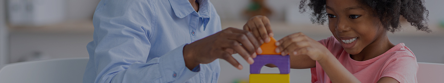 A school guidance counselor helps a young student with building blocks.