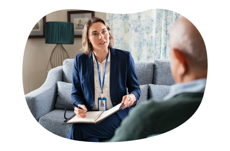 Social worker sitting on a couch speaking with a client at their home. Social worker sitting on a couch speaking with a client at their home.