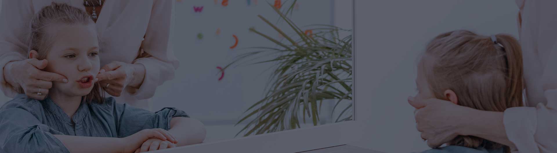 Close-up of reflection in the mirror of young girl exercising pronunciation with speech therapist. Close-up of reflection in the mirror of young girl exercising pronunciation with speech therapist.