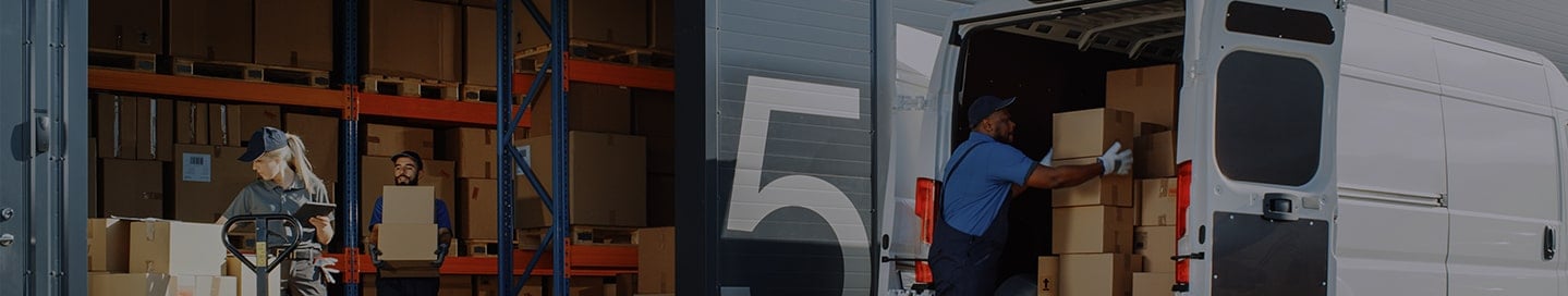 A transportation business's employee loads boxes into a van. A transportation business's employee loads boxes into a van.
