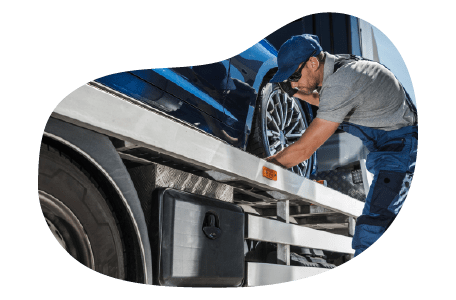 A technician checks the tires on a vehicle loaded onto a car hauler.