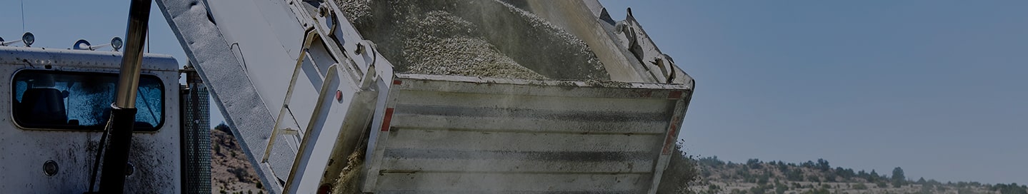 A dump truck unloading gravel at a job site.