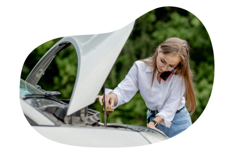 A person checking a car’s engine with the hood open.