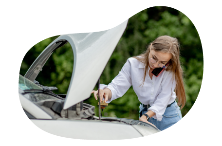 A person checking a car’s engine with the hood open.