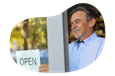 A small business owner hanging the "open" sign at their new store location