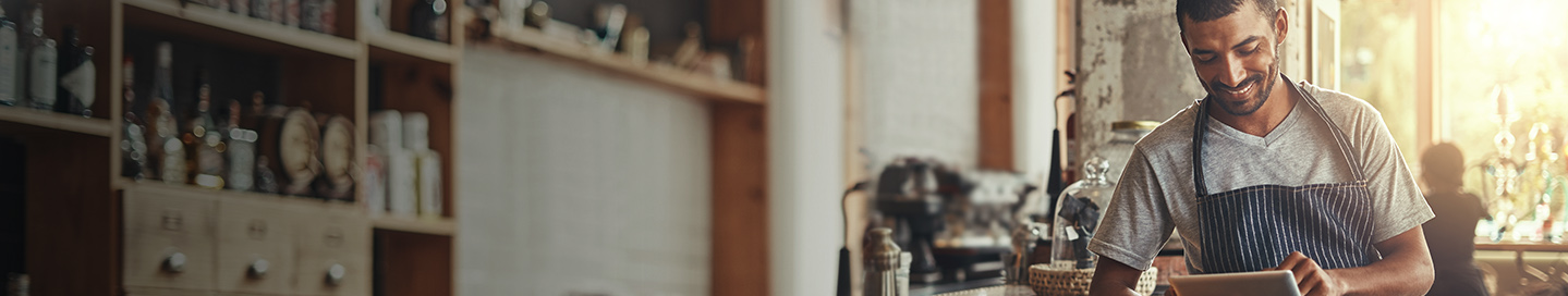 Business owner working on tablet at a counter. Business owner working on tablet at a counter.